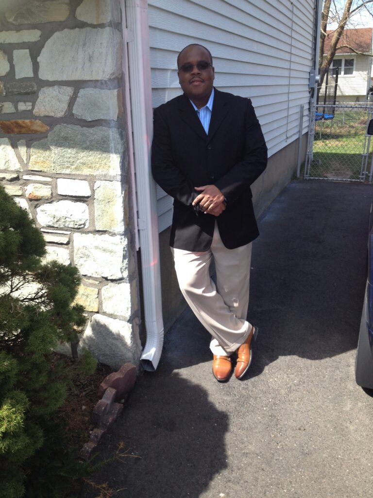 Jean Wilkins Paul in a black blazer, smiling outside his home office